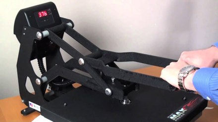 Close up of person using Hotronix Maxx Digital Cap Heat Press with their hands holding the press handle down